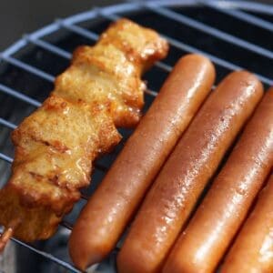 A grill with hot dogs and some meat on it