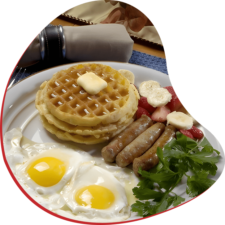A plate of food with eggs, sausage and waffles.